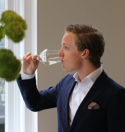 A young man drinking white wine