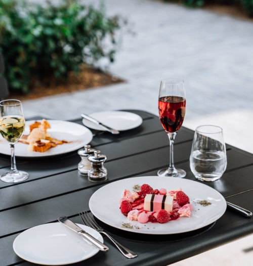 A desert with red fruit and a glass of wine on a terrace