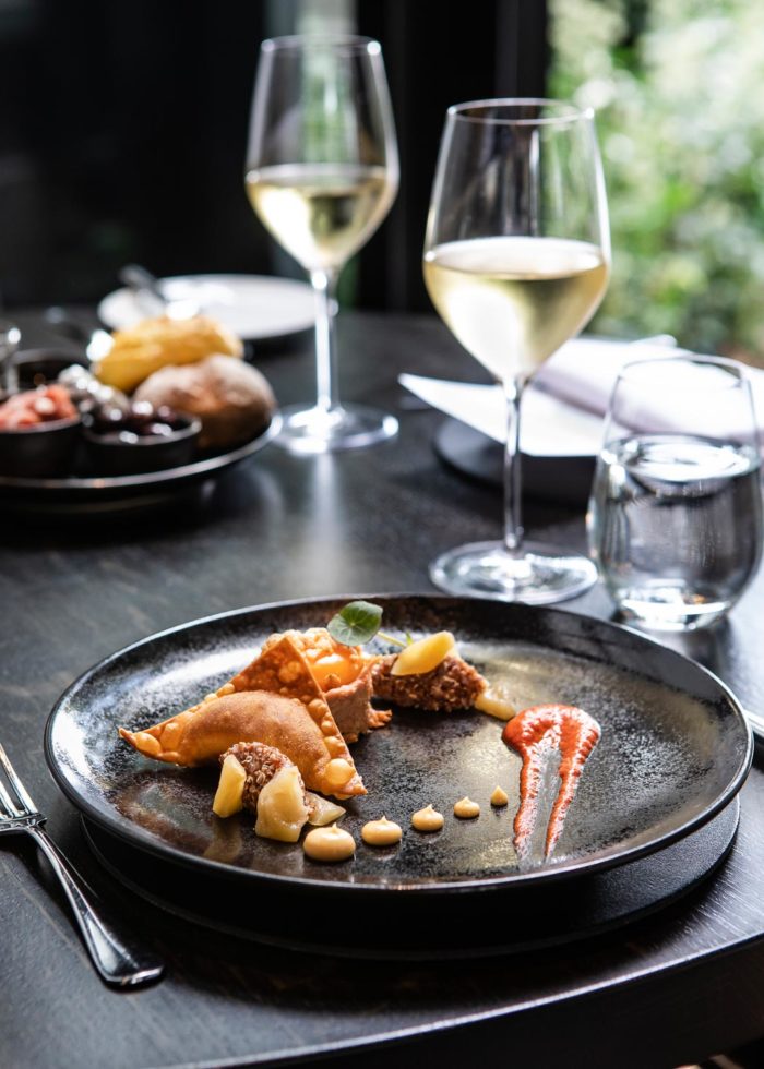 Dishes on black plates with white wines at Coperto Restobar in Zwolle